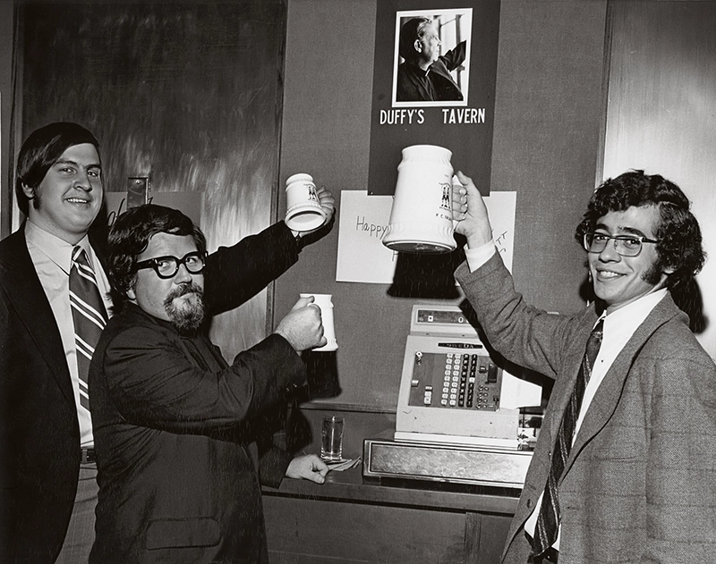 Two students and a Dominican priest raise beer mugs in the 21 Club, the first student bar at Providence College.
