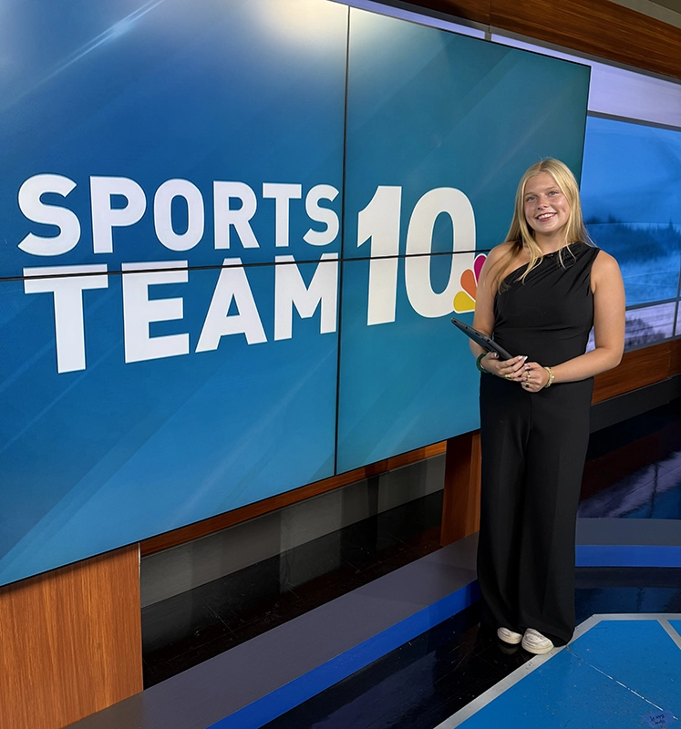 Caroline Austin '26 in front of the "Storm Team 10" logo while interning with WJAR-TV.