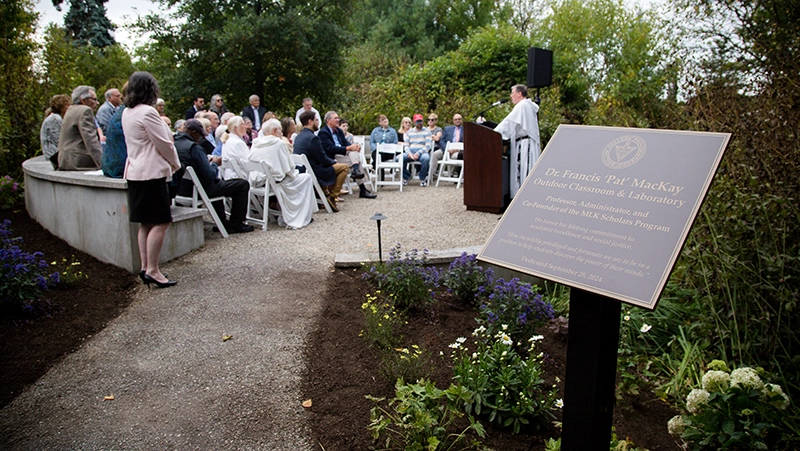 College President Rev. Kenneth R. Sicard speaks in the outdoor classroom as the crowd watches during the MacKay dedication.