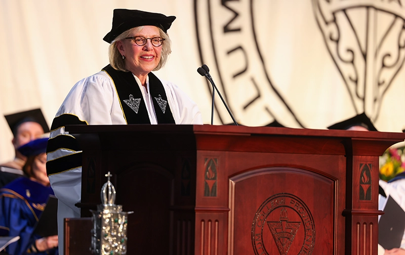 Woman in cap and white gown at lectern