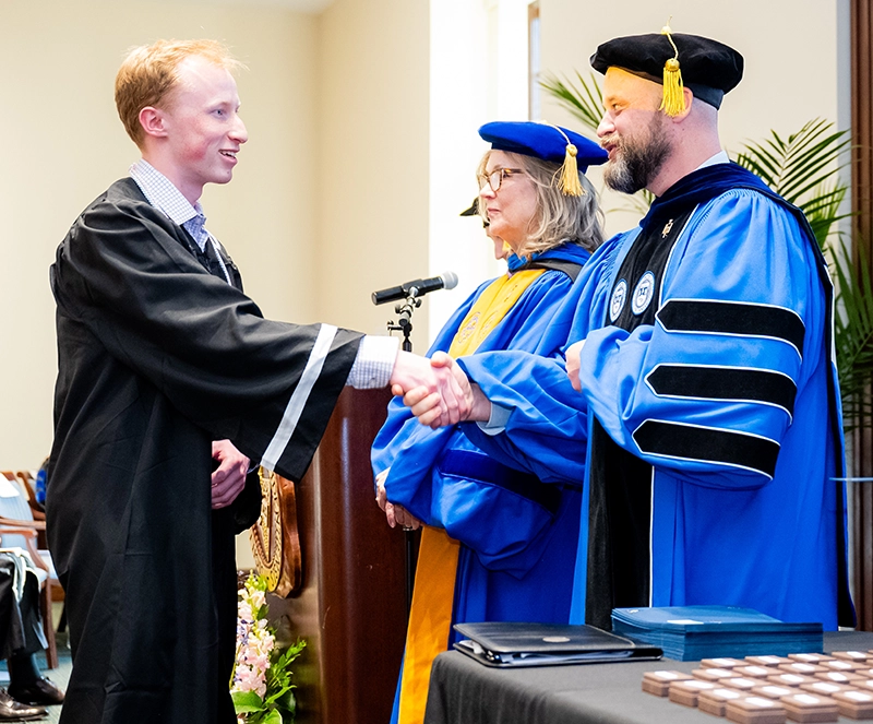 Connor Enestvedt '26 is congratulated by professors Joan Branham, Ph.D., and during his induction into Phi Beta Kappa in April 2025.
