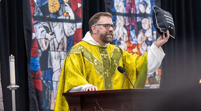 Rev. Jordan Zajac, O.P. '04 displays the pillow during the Senior Ring Weekend Mass in Peterson Recreation Center.