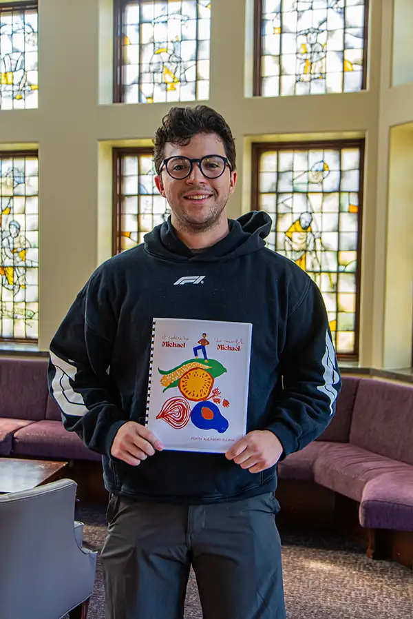 Alejandro Guzmán '26 poses with the cover of his short story, “El Poderoso Michael/The Powerful Michael," which was published in Our Heritage: Short Stories of Bilingual Youth in the Northeastern United States.
