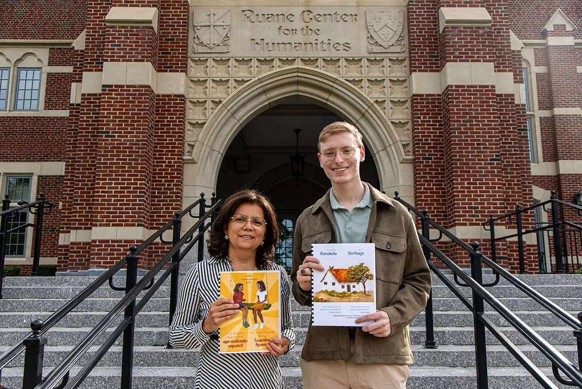 Ana Cecilia Iraheta, Ph.D., and Jake R. Turcotte ’23, ’26G, pose in front of the Ruane Center for the Humanities with Our Heritage: Short Stories of Bilingual Youth in the Northeastern United States, which they co-edited.