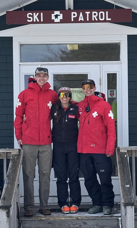 Three people in ski parkas stand under a "Ski Patrol" sign at Loon Mountain.