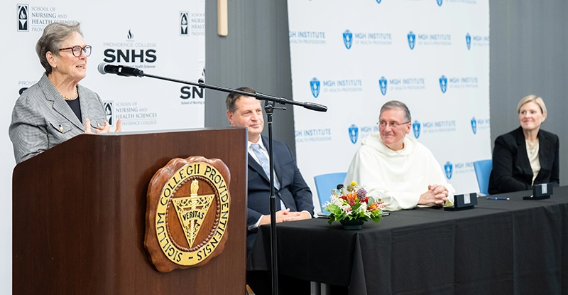 Paula Milone-Nuzzo, Ph.D., president of the MGH Institute of Health Professions, speaks at the signing ceremony. Also pictured are Kyle McInnis, founding dean of PC's School of Nursing and Health Sciences; PC President Rev. Kenneth R. Sicard, '78, '82G; and Maura Abbott, Ph.D., dean of the School of Nursing at MGH Institute of Health Professions.