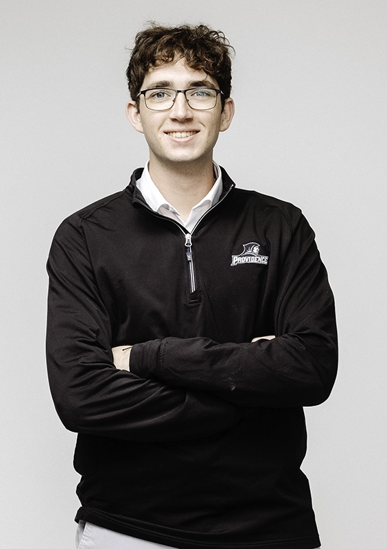 Nathan Cross '26 stands with his arms folded wearing a black Friars quarter zip pullover.