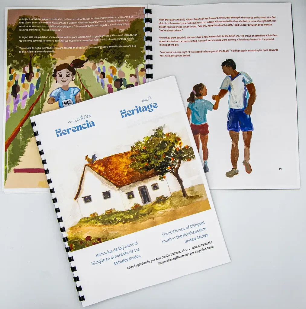 A shot of the cover of Our Heritage: Short Stories of Bilingual Youth in the Northeastern United States. In the background, the spiral bound book is open to a page.