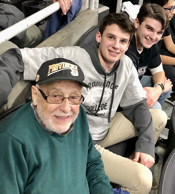 A grandfather and his two grandsons sitting in the stands at a basketball game.