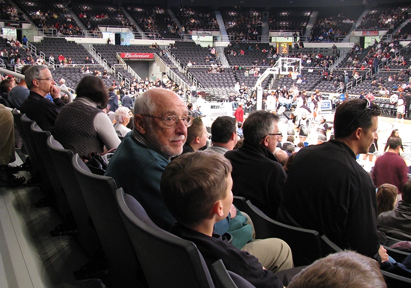 John Puelo and his grandson sit in the stands at Amica Mutual Pavilion watching a Providence College Friars basketball game.
