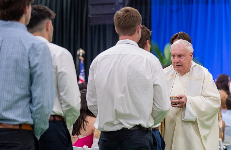 Father James Quigley, O.P. '60 distributes communion at the Commencement Mass in 2025.