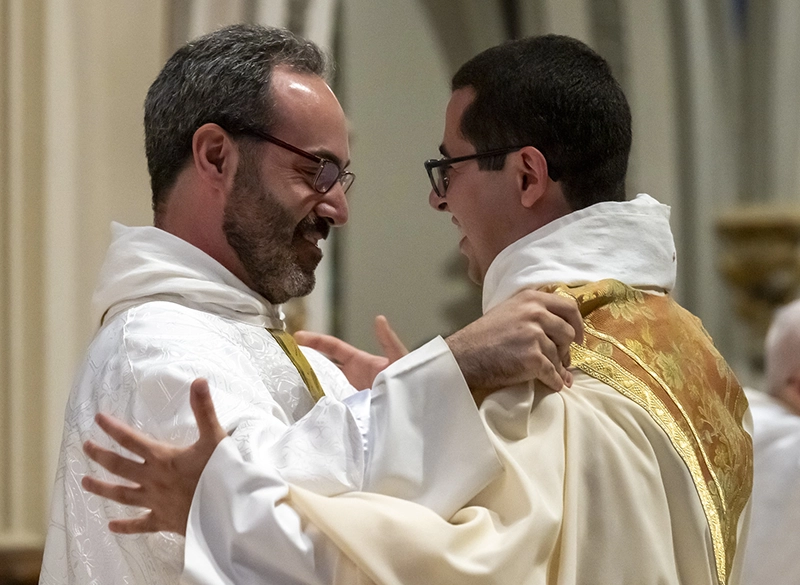 Priests greet each other warmly during ordination ceremony.