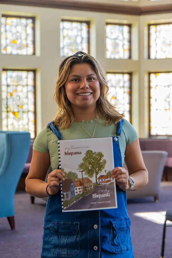 Marilyn Roque '26 poses with the cover of her short story, "Orgullosamente Hispana/Proudly Hispanic," which was published in Our Heritage: Short Stories of Bilingual Youth in the Northeastern United States.