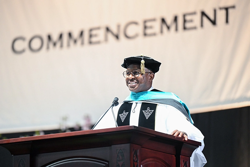 Man in cap and gown at lectern.