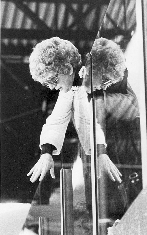 Helen Bert, the first director of women's athletics, leans over plexiglass to talk to women's hockey players in a 1970s photo.