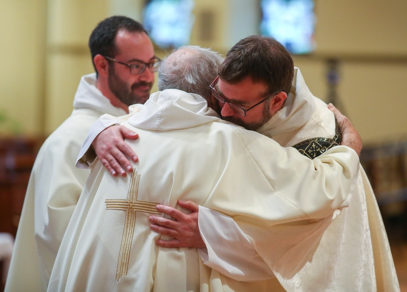 Rev. Jordan Zajac, O.P. '04 hugs Rev. John Reid, O.P. during Father Jordan's ordination in St. Dominic Chapel in May 2020. At left is Rev. Michael Weibley, O.P.