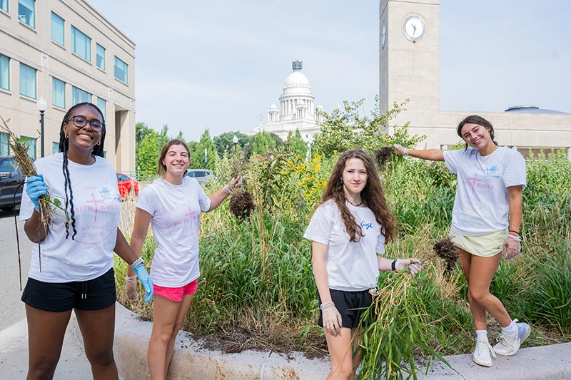 Class of 2028 students participating in the FaithWorks program helped weed around the Amtrak station in Providence.