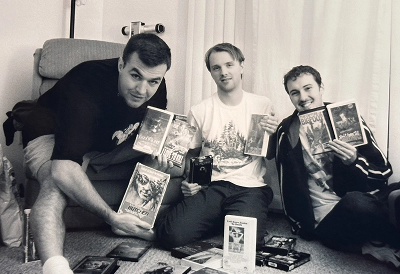 From left, Matt Farley '00, Charlie Roxburgh '99, and Tom Scalzo '00 with the horror movies they would watch for creative inspiration in their film-making.