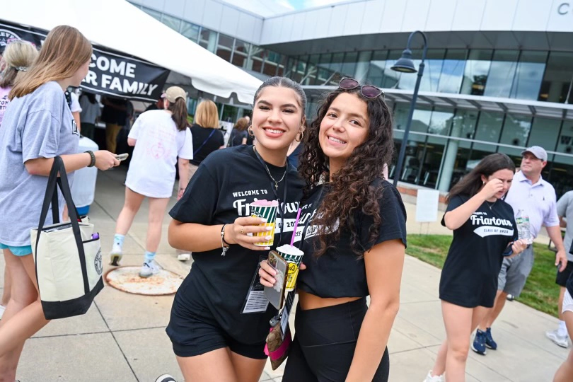 Two women holding cups of Dell's frozen lemonade stand on the plaza outside Slavin Center and the Concannon Fitness Center.