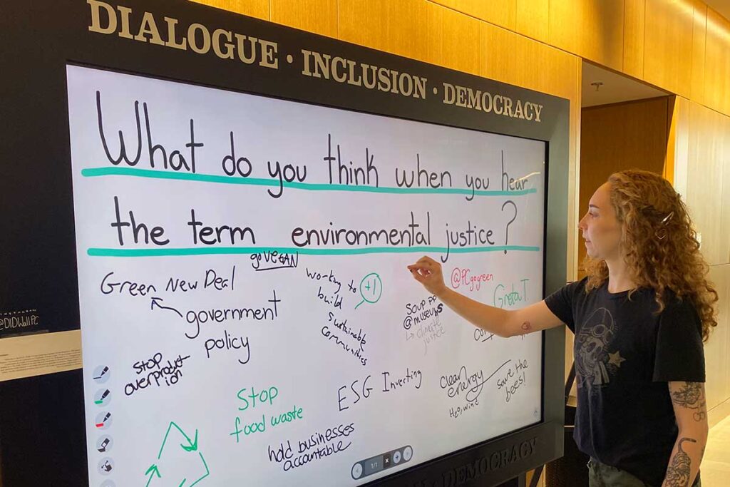 student writes on the electronic DID wall in the Ryan Center for Business Studies
