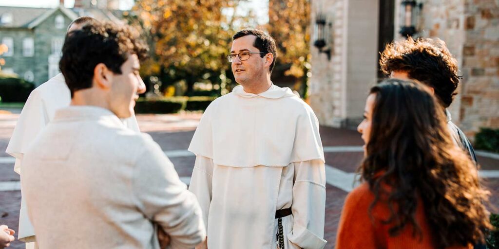 Father Simon Teller converses with students outside St. Dominic Chapel