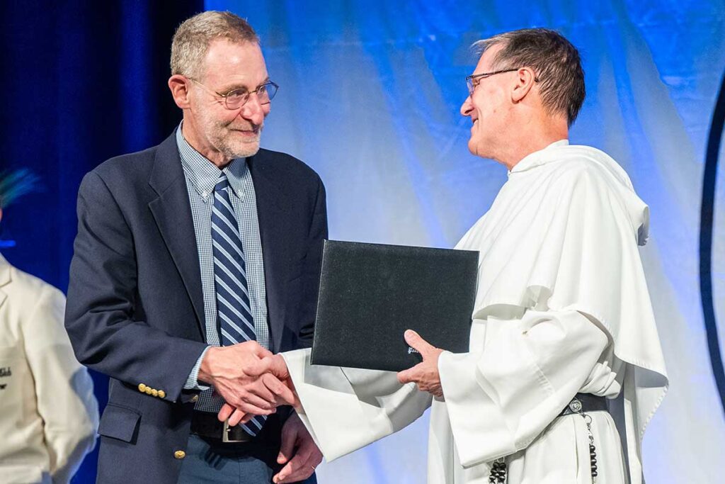 Ian Levy, Ph.D., professor of theology, receives the Faculty Scholar Award from Father Sicard