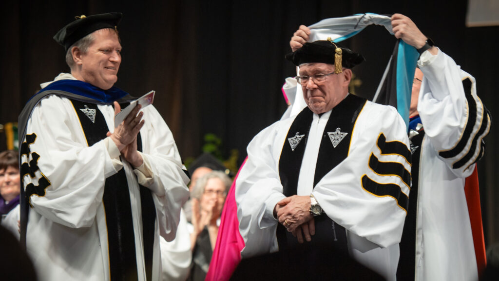 Raymond L. Sickinger, Ph.D. '71, emeritus professor of history, receives an honorary doctor of education degree. At left is Very Rev. Allen B. Moran, O.P.