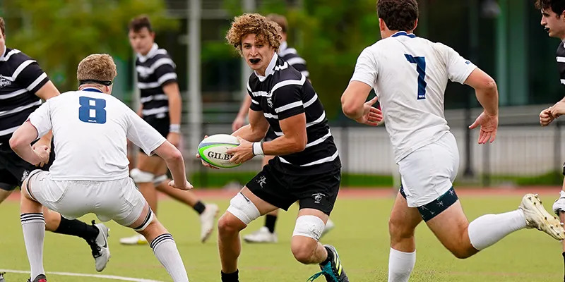 Billy Adams '25 running with ball during a rugby match
